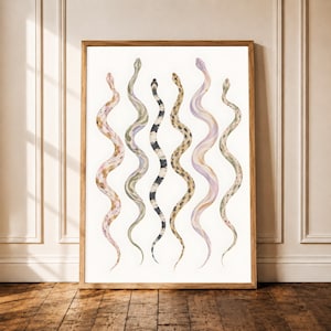Op de afbeelding: Een ingelijste verticale wandkunstprint met zes aquarelslangen in een rij. De slangen vertonen verschillende patronen en kleuren, waaronder roze, groen, zwart, beige en lavendel, allemaal tegen een effen witte achtergrond.