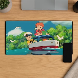 May include: A rectangular desk mat featuring a colourful anime-style illustration of a young person in a yellow shirt and captain's hat steering a small white and red boat, with a red-haired character sitting on the roof amidst a lush green forest.