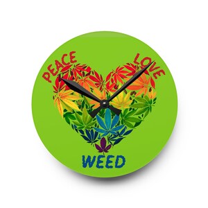 May include: A round wall clock with a bright lime green background. The center features a heart-shaped collage of multi-colored cannabis leaves in red, orange, yellow, blue, and purple. The text PEACE LOVE is arched above, and WEED is below.