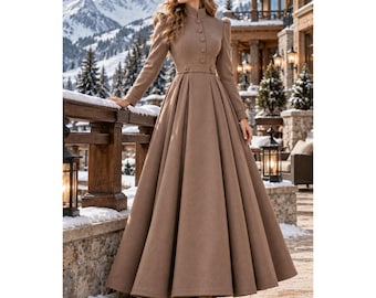 May include: A floor-length, long-sleeved dress in a solid tan color. The dress features a high collar, a row of buttons down the front bodice, a fitted waist with a horizontal band, and a full, pleated skirt that flares out toward the hem.