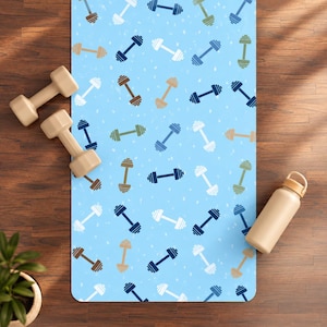 Peut inclure: Un tapis de yoga bleu clair avec un motif répétitif d'haltères de différentes couleurs, notamment bleu marine, blanc, beige et vert olive. Deux haltères beiges et une gourde beige sont posés sur le tapis, qui présente une texture blanche mouchetée.