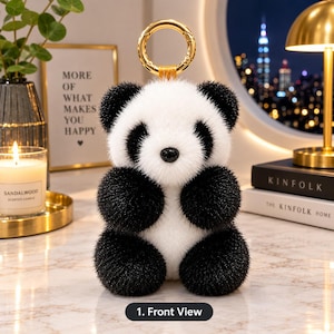 Può includere: Un portachiavi a forma di panda in peluche con corpo in pelliccia sintetica testurizzata bianca e nera, un piccolo naso nero e un anello in metallo dorato fissato sulla parte superiore. Il panda ha orecchie nere arrotondate, macchie nere intorno agli occhi e arti neri.