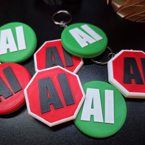 May include: A collection of circular and octagonal keychains featuring the letters AI. The circular keychains are green with white letters, while the octagonal keychains are red with black letters. Each piece includes a metal ring for attachment.