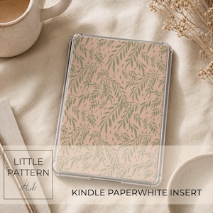 Puede incluir: Una lámina rectangular para Kindle Paperwhite con un patrón repetitivo de hojas de sauce en color verde salvia sobre un fondo rosa empolvado. La lámina está protegida por una funda transparente con esquinas redondeadas y acabado liso.