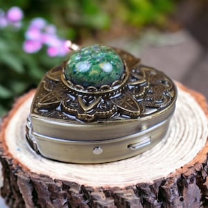 May include: A heart-shaped music box with an ornate design and a green gemstone top.