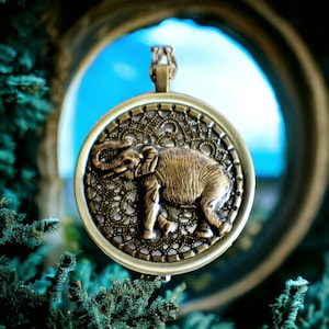 Music box locket, round  locket with music box inside, in bronze with bronze elephant on cover