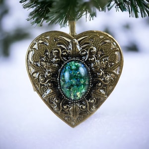 May include: A heart-shaped ornament with an ornate gold finish and a green gemstone in the center.