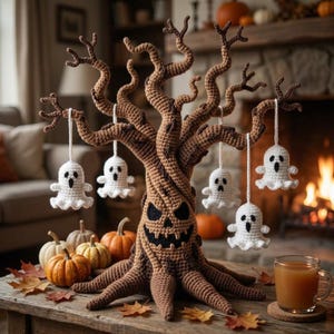 Puede incluir: Un árbol de ganchillo marrón con una cara de calabaza tallada, con varios adornos de fantasmas blancos de ganchillo colgando de sus ramas, rodeado de pequeñas calabazas naranjas y hojas de otoño esparcidas.
