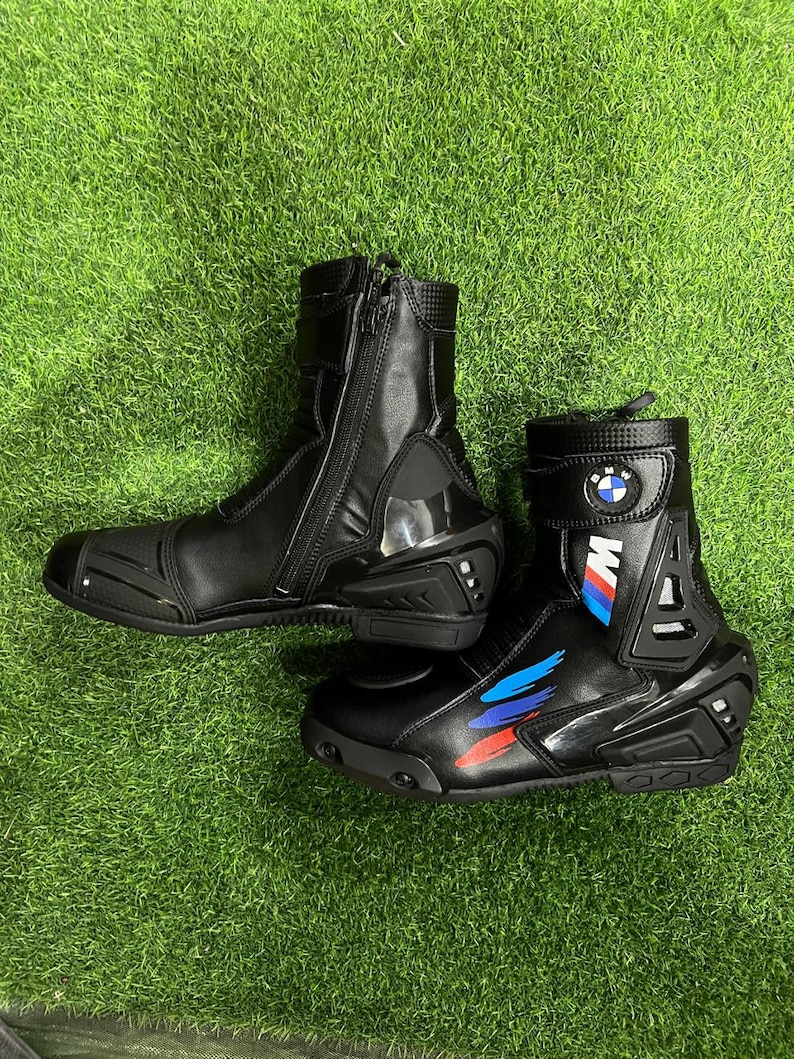 Puede incluir: Un par de botas de moto negras con cremallera lateral, protecci&oacute;n reforzada en el tal&oacute;n y el tobillo, y el logotipo de BMW. Las botas presentan rayas gr&aacute;ficas azules, moradas y rojas en el lateral e incluyen un cierre de correa en la parte superior.
