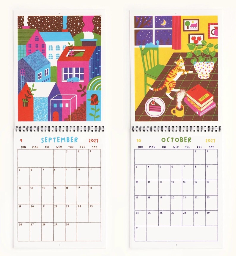 May include: A 2027 wall calendar showing September and October pages. September features a colorful town illustration, while October depicts a cat on a table with a cake and coffee. Each page includes a grid with days of the week and dates.
