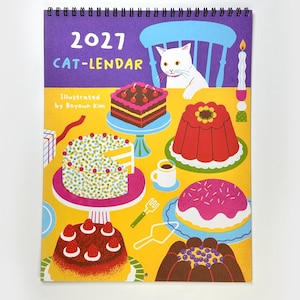 May include: A 2027 wall calendar titled 2027 CAT-LENDAR Illustrated by Boyoun Kim, featuring a white cat sitting at a yellow table filled with various colorful cakes, desserts, a small cup, a fork, a cake server, and a lit candle.