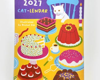May include: A 2027 wall calendar titled 2027 CAT-LENDAR Illustrated by Boyoun Kim, featuring a white cat sitting at a yellow table filled with various colourful cakes, desserts, a small cup, a fork, a cake server, and a lit candle.