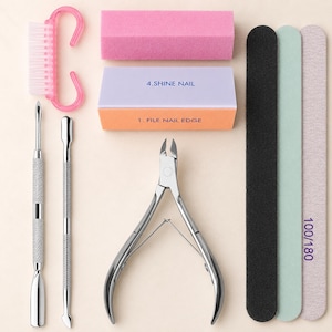 Op de afbeelding: Een manicure set bestaande uit een roze nagelborstel, een roze blokvijl, een lavendelkleurig en oranje blok met de tekst 4.SHINE NAIL en 1. FILE NAIL EDGE, twee metalen nagelriemduwers, een roestvrijstalen tang en drie lange nagelvijlen.