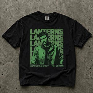 May include: A black short-sleeve t-shirt featuring a green graphic of Hal Jordan. The design includes the repeated word LANTERNS in the background and the text: IN BRIGHTEST DAY, IN BLACKEST NIGHT, NO EVIL SHALL ESCAPE MY SIGHT HAL JORDAN.
