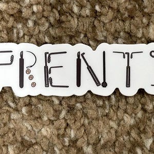 May include: White sticker with the word "APPRENTICE" written in black letters. Each letter is made up of a different tool, such as a wrench, pliers, and a screwdriver.