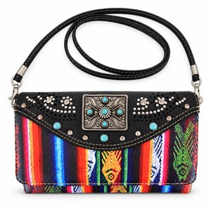 May include: A black crossbody bag featuring a multi-colored striped fabric panel with fish motifs. The black flap has laser-cut floral patterns, clear rhinestones, and a central silver-toned rectangular buckle with turquoise-colored stones.