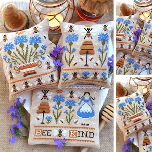 Può includere: Cuscini decorativi beige con ricami a punto croce raffiguranti api, alveari e fiori blu. Un cuscino presenta la scritta "BEE KIND". I cuscini sono quadrati e hanno un'estetica rustica e fatta a mano.