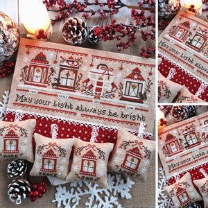 May include: A cross-stitch design featuring red and brown lanterns with the text "May your light always be bright." The design includes small pillows with lantern motifs and the words "Hope," "Peace," "Joy," and "Love."