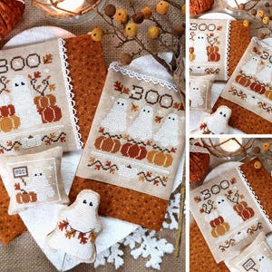 May include: A set of four cross-stitch embroidery patterns featuring ghosts, pumpkins, and the word "BOO". The patterns are displayed on fabric with a brown and orange floral print.
