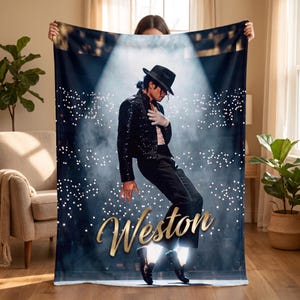 May include: A rectangular fleece blanket featuring a printed image of a performer in a black sequined jacket, black trousers, and a fedora, dancing under a spotlight. The name Weston is printed in large, gold, cursive script across the lower center.