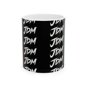 May include: A black ceramic mug featuring a repeating white brushstroke pattern of the letters JDM arranged in vertical columns around the exterior surface. The interior of the mug is white, and the handle is visible on the right side of the object.