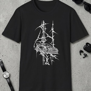 Könnte beinhalten: Ein schwarzes Kurzarm-T-Shirt mit einem weißen Grafikdruck auf der Brust. Das Design zeigt eine Strichzeichnung eines Sportwagens, zentriert in einem komplexen, scharfen, sternartigen Netzmuster, das sich vertikal über den Stoff erstreckt.