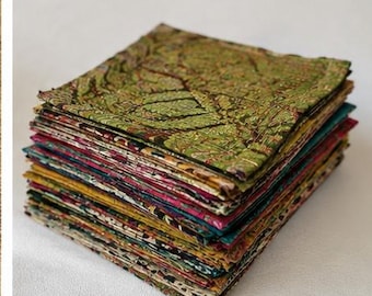 May include: A tall stack of square fabric pieces featuring a variety of intricate patterns and colors. The top piece is primarily green with a dark, detailed botanical print. The layers below display diverse hues including yellow, pink, and teal.
