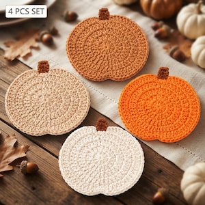 May include: A 4 pcs set of round, crocheted pumpkin coasters in orange, light orange, beige, and cream colors. Each coaster features a small, brown, textured stem at the top, crafted with a circular stitch pattern that radiates from the center.