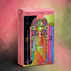 May include: A rectangular deck of Pink A.E. Classic Tarot cards in a pink box. The front features a colourful illustration of a seated figure wearing a crown, flanked by a black pillar marked with a B and a blue pillar marked with a J.