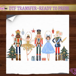 May include: A DTF transfer sheet featuring a holiday illustration with two nutcrackers, a fairy in a gold dress, a dancer in a blue dress, and a mouse king. The design includes two Christmas trees, wrapped gifts, and ornaments on a white background.
