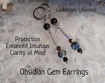 May include: Obsidian Gem Earrings with silver hoops, black beads, and iridescent blue and white gemstone accents. The earrings are on a white background with the text "Goddesses Unlimited", "Protection", "Enhanced Intuition", "Clarity of Mind", and "Obsidian Gem Earrings".
