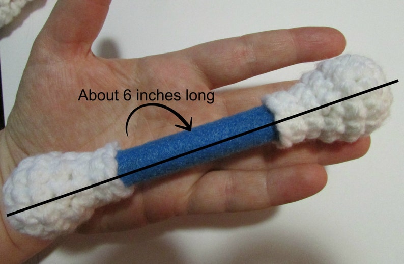 May include: A blue and white crocheted toy bone, about 6 inches long. The bone is made of a blue foam tube covered in white crocheted fabric.