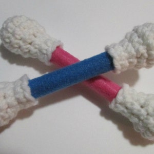 May include: Two crocheted white cotton balls attached to a blue and pink stick. The stick is covered in felt.