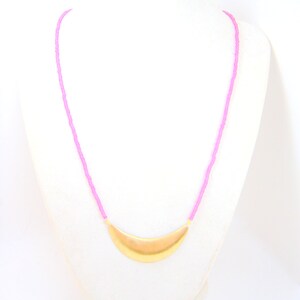 May include: A pink beaded necklace with a gold crescent moon pendant.