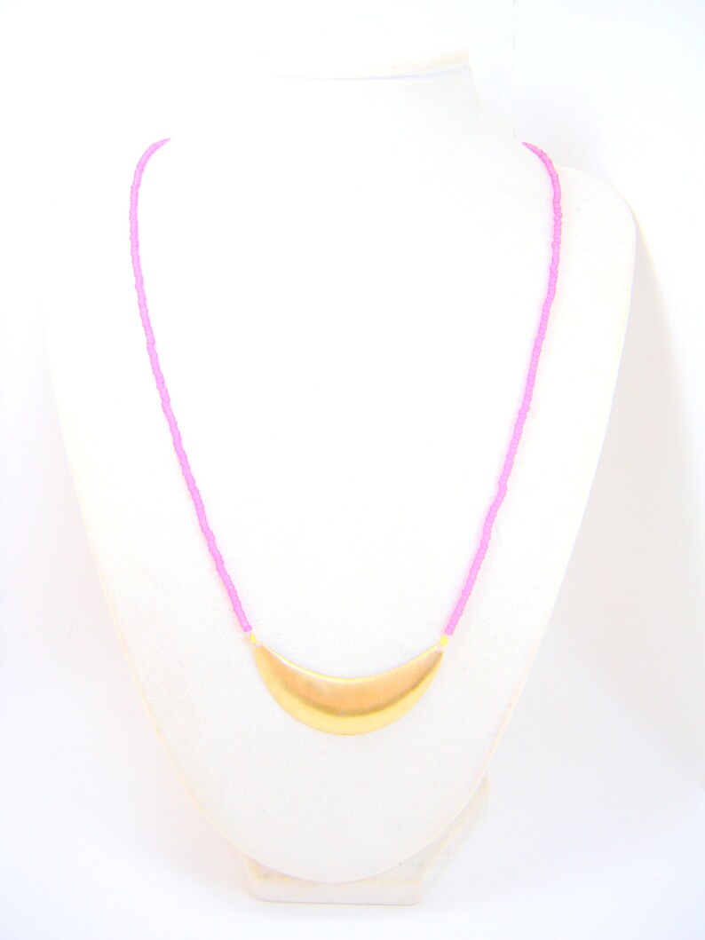 May include: A pink beaded necklace with a gold crescent moon pendant.