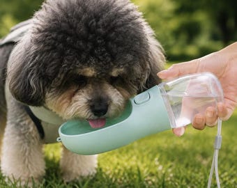 Peut inclure: Une gourde portable pour animal de compagnie composée d'un réservoir en plastique transparent fixé à un bol abreuvoir en forme de gouttière vert menthe clair, avec un bouton-poussoir et une dragonne gris clair pour le transport.