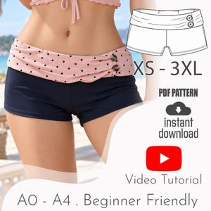 Könnte beinhalten: Dunkelblaue Badeshorts mit einem breiten, umgeschlagenen Bund in Hellrosa mit schwarzen Punkten und zwei braunen Knöpfen an der Seite. Das Bild enthält den Text: XS - 3XL, PDF PATTERN, instant download, Video Tutorial, A0 - A4 . Beginner Friendly.