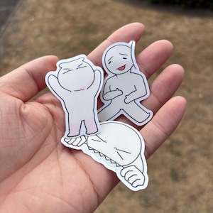 May include: Three die-cut vinyl stickers featuring cartoon characters with simple line art. One character stands with arms raised, another sits with a smiling expression, and the third is depicted with a wide, toothy grin and outstretched arms.