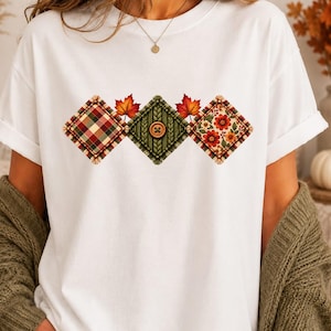 May include: A white short-sleeved t-shirt featuring a graphic print of three diamond-shaped patches arranged horizontally. The patches display a red and green plaid pattern, a green knit texture with a central button, and a floral print.