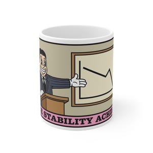 May include: A white ceramic mug featuring a cartoon illustration of a person in a suit standing at a podium, gesturing toward a downward-trending line graph on a framed board. Below the illustration, the text reads STABILITY ACHIEVED.