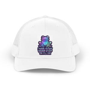 May include: A white trucker hat featuring a graphic of a colorful, iridescent frog with a handprint on its chest. Below the frog, the text reads I HAVE TO SAY WEIRD STUFF OR I'LL DIE in a bold, dark, and stylized font with a purple and blue gradient.