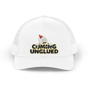 Pode incluir: Um boné trucker branco com um gráfico de um personagem de frasco de cola angustiado com tampa vermelha e o texto COMING UNGLUED em letras azul-marinho em negrito com contorno amarelo. O boné tem um painel frontal sólido e malha atrás.