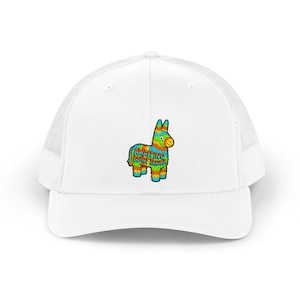 May include: A white trucker cap featuring a colourful piñata graphic on the front panel. The piñata is decorated with bright stripes of blue, green, orange, and yellow, and includes the text AWAITING BLUNT TRAUMA printed in bold letters.