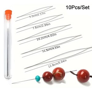 May include: A 10-piece set of collapsible eye beading needles in a clear storage tube with an orange cap. The needles range in length from 2.17 inches to 5.04 inches. One needle is shown threaded with a turquoise bead and three red beads.