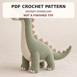 Peut inclure: Un jouet dinosaure au crochet avec un corps vert sauge, une poitrine couleur crème et de petites pointes beiges le long du dos et de la queue. Le texte PDF CROCHET PATTERN INSTANT DOWNLOAD NOT A FINISHED TOY est superposé en noir et rouge.