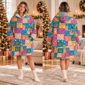 Könnte beinhalten: Ein übergroßer Kapuzenpullover mit einem bunten Patchwork-Muster aus Schmetterlingen, akustischen Gitarren und Blumenmotiven in den Farben Türkis, Pink, Gelb und Lila. Das Kleidungsstück verfügt über eine große Vordertasche.