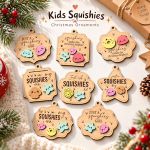 Può includere: Otto decorazioni natalizie in legno di varie forme, ognuna con testo inciso e piccoli personaggi squishy sorridenti e colorati. Il testo include frasi come Just a squishies girl, In my squishies era e Squishies makes the christmas brighter.