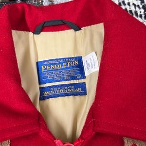 May include: A close-up of a red wool jacket collar with a cream lining. The jacket has a Pendleton label with text including "100% Pure Virgin Wool" and "High Grade Western Wear."