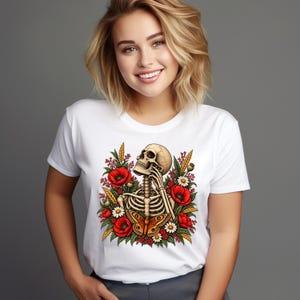 May include: A white short-sleeved t-shirt featuring a graphic print of a human skeleton resting its chin on its hand, surrounded by red poppy flowers, white daisies, green foliage, stalks of wheat, and a large orange and brown butterfly.