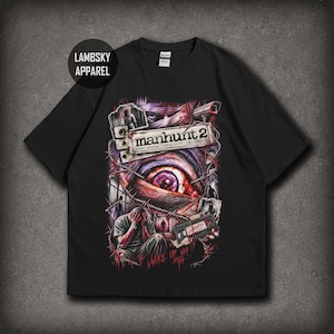May include: A black short-sleeve t-shirt featuring a graphic print with the text "manhunt 2" and "CONFIDENTIAL". The design includes a large eye, a person with their head in their hands, barbed wire, and surveillance imagery in dark tones.